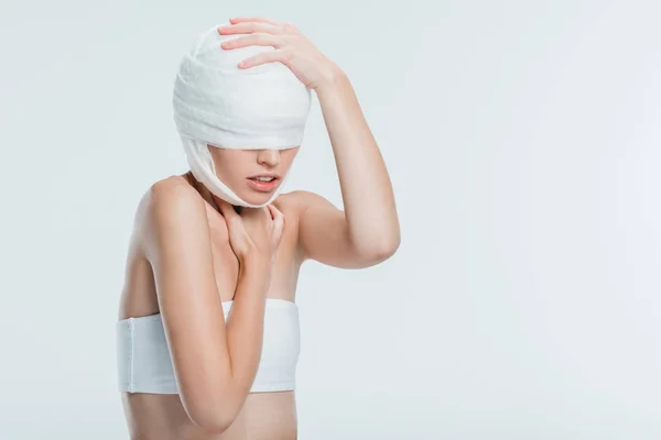 Femme avec des bandages touchant la tête isolé sur blanc — Photo de stock