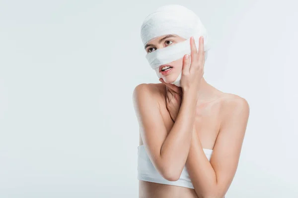 Frau mit Verbänden, die Kopf isoliert auf weiß berühren — Stockfoto
