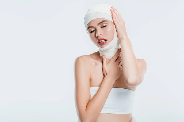 Красива доросла жінка після пластичної хірургії торкається голови ізольовано на білому — стокове фото