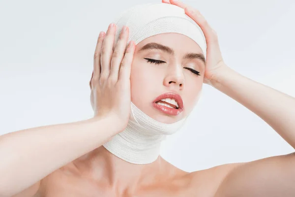 Primo piano di adulto bella donna dopo chirurgia plastica toccare la testa isolata su bianco — Foto stock