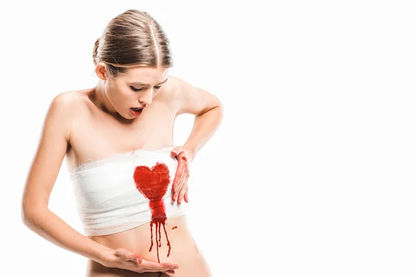 Adult woman in bandages looking at bloody heart isolated on white — Stock Photo