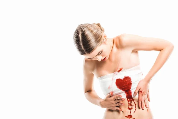 Adult woman in bandages looking at bloody heart isolated on white — Stock Photo