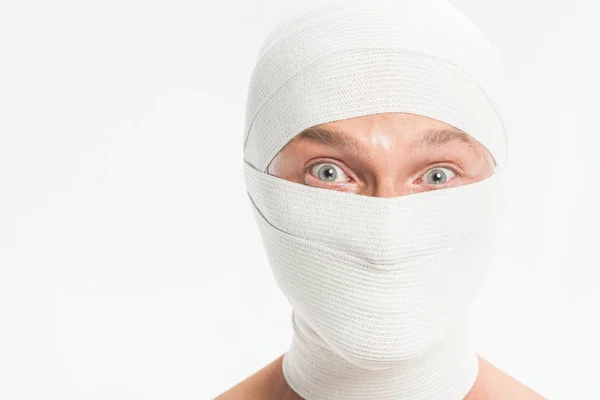 Primer plano de la cara del hombre cubierta con vendajes blancos después de la cirugía plástica aislada en blanco - foto de stock