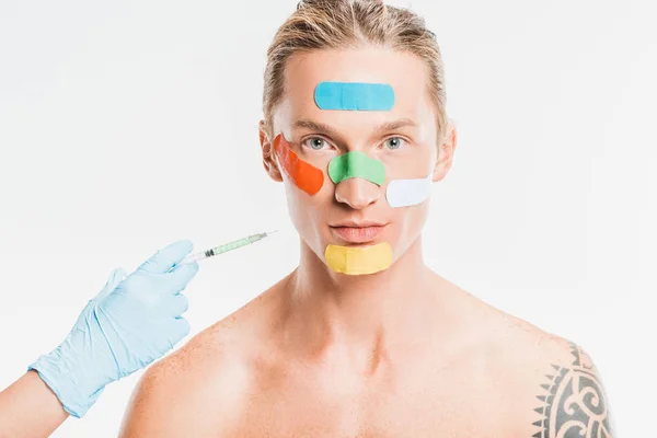 Médecin faisant l'injection à l'homme avec des patchs multicolores sur le visage isolé sur blanc — Photo de stock