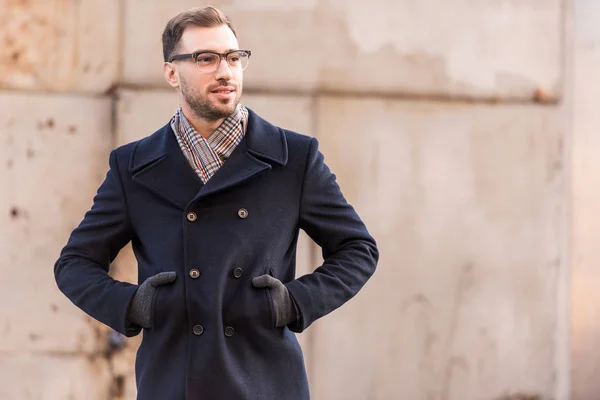 Schöner Mann, der mit den Händen in den Taschen nahe der rustikalen Metallwand steht — Stockfoto