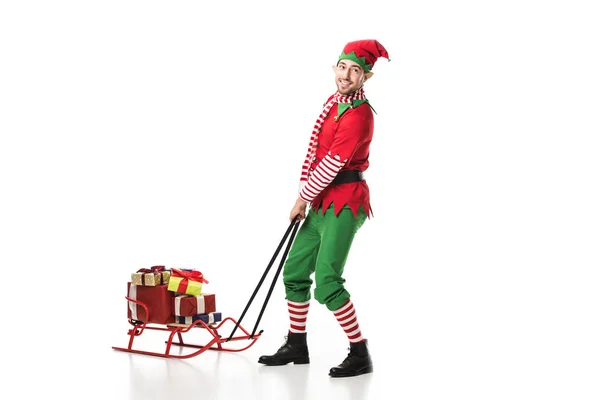 Mann im Weihnachtselfenkostüm zerquetscht Stapel von Geschenken isoliert auf weiß — Stockfoto