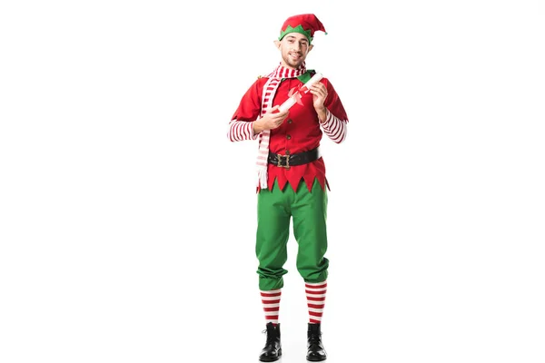 Sorridente homem no Natal elfo traje segurando wishlist rolo e olhando para câmera isolada no branco — Fotografia de Stock