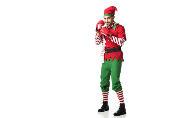 Hombre en traje de elfo de Navidad con guantes de boxeo rojos y listo para la lucha aislado en blanco - foto de stock