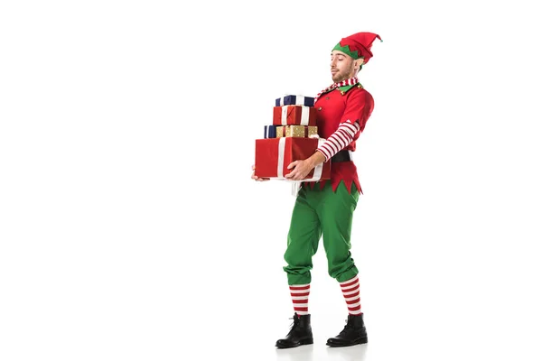 Hombre en traje de elfo de Navidad llevando montón de regalos aislados en blanco - foto de stock