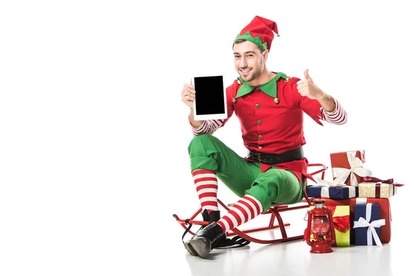 Homem em traje de elfo de natal sentado no trenó e segurando tablet com tela em branco isolado no branco — Fotografia de Stock