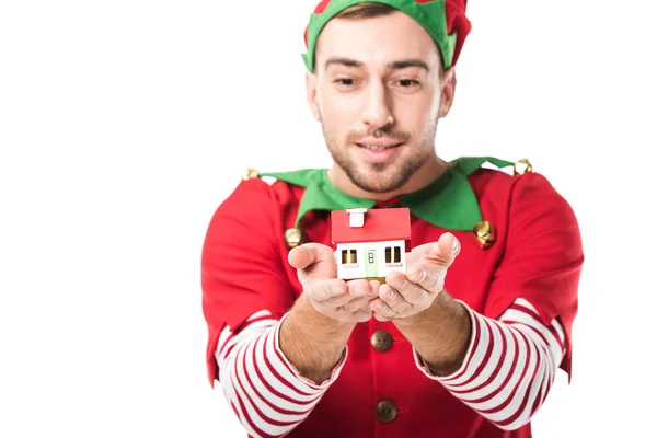 Homme en costume d'elfe de Noël tenant modèle de maison isolé sur blanc, vente immobilière et concept d'assurance — Photo de stock