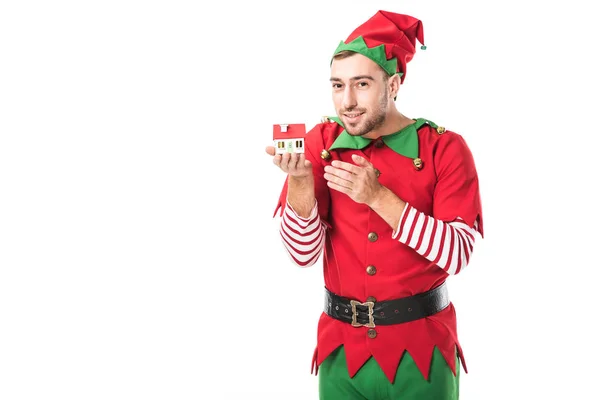 Homem em Natal elfo fantasia segurando casa modelo isolado em branco, venda de imóveis e conceito de seguro — Fotografia de Stock