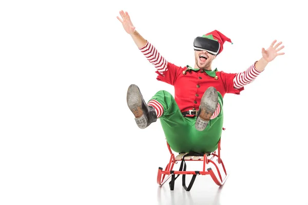 Uomo eccitato in costume elfo natale a cavallo slitta e indossando cuffia realtà virtuale isolato su bianco — Foto stock