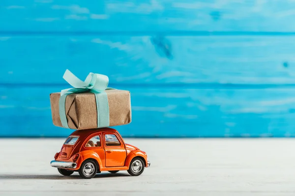 Close-up shot of toy vehicle with gift box on blue wooden background — Stock Photo