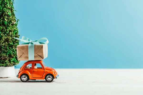 Primer plano del vehículo de juguete con caja de regalo sobre fondo azul - foto de stock