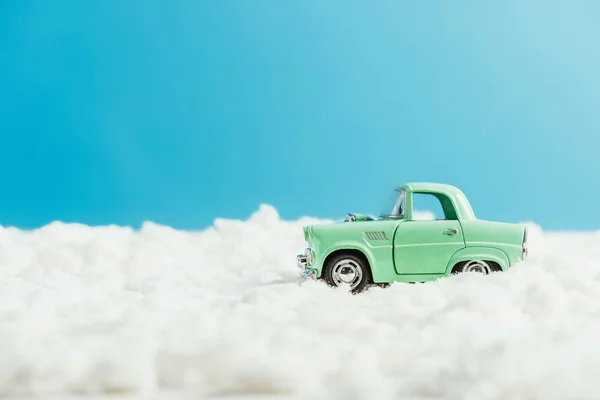 Vue latérale de la voiture jouet chevauchant par la neige en coton sur fond bleu — Photo de stock