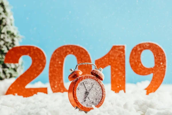 Великі червоні номери 2019 року з будильником, що стоїть на снігу на синьому фоні, концепція нового року — стокове фото