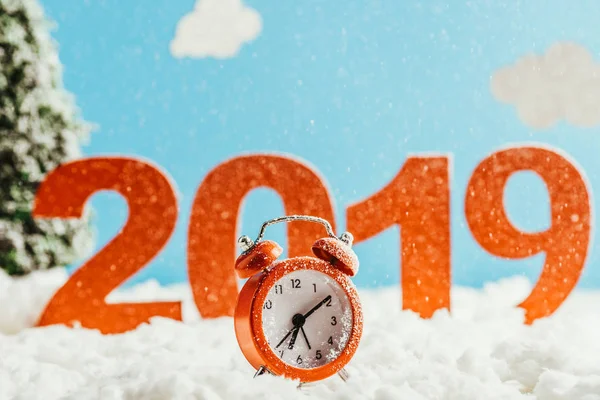 Grandes números rojos 2019 con reloj despertador vintage de pie sobre la nieve sobre fondo azul, concepto de año nuevo - foto de stock