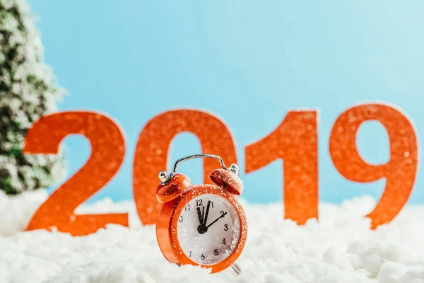 Grandes números rojos 2019 con reloj despertador vintage de pie sobre la nieve sobre fondo azul, concepto de año nuevo - foto de stock