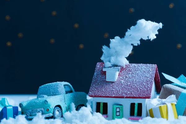Gros plan de voiture miniature avec cadeaux de Noël et maison couverte de neige dans la nuit — Photo de stock