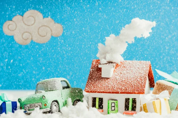 Close-up shot of miniature car with christmas gifts and house covered with snow — Stock Photo