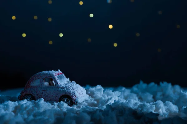 Primer plano de coche de juguete de pie en la nieve en la noche bajo el cielo estrellado, el concepto de Navidad - foto de stock