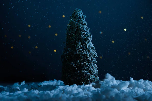 Gros plan de l'arbre de Noël miniature debout dans la neige la nuit — Photo de stock