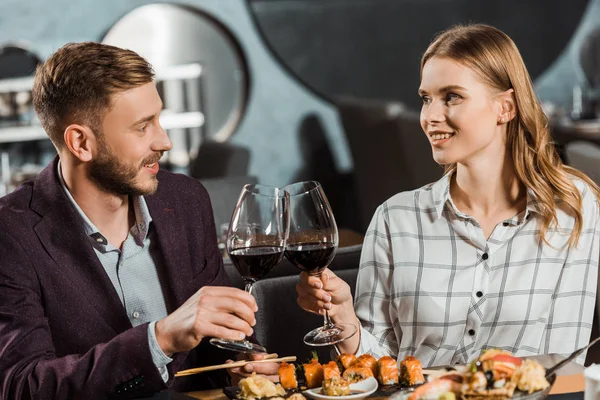 Young adult couple in love clinking while having dinner in restaurant — Stock Photo