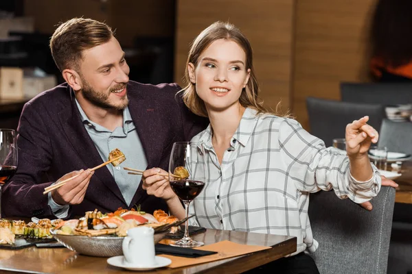 Atractiva pareja cenando mientras una mujer señala algo en el restaurante - foto de stock