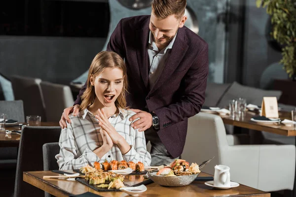 Handsome man with his happy surprised girlfriend in restaurant — Stock Photo