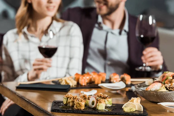 Partial view of couple eating sushi and drinking wine while having date in restaurant — Stock Photo