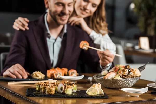 Pareja de adultos jóvenes comiendo sushi en el restaurante - foto de stock