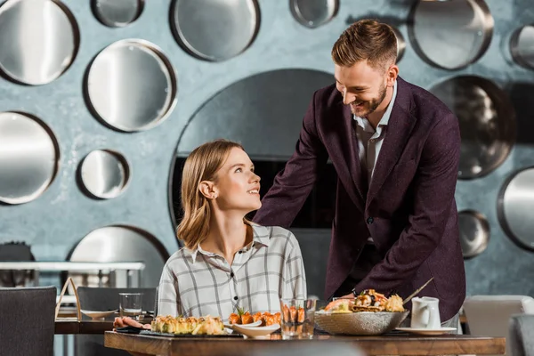 Mann kümmert sich im Restaurant um seine glückliche attraktive Freundin — Stockfoto