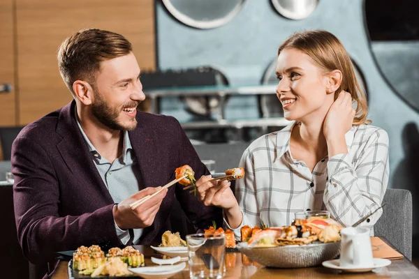 Atractiva pareja sonriente cenando en el restaurante - foto de stock