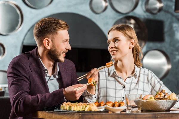 Happy young adult couple looking at each other while having dinner together in restaurant — Stock Photo