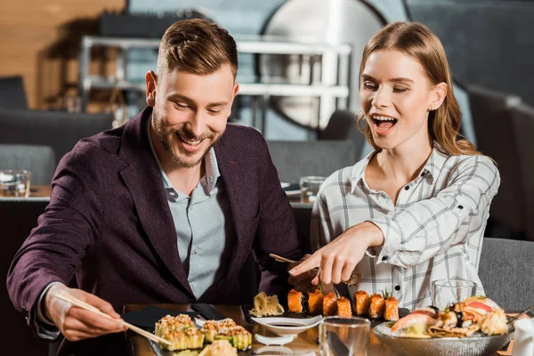 Béatifique femme heureuse pointant du doigt quelque chose pendant que le couple dîne au restaurant — Photo de stock