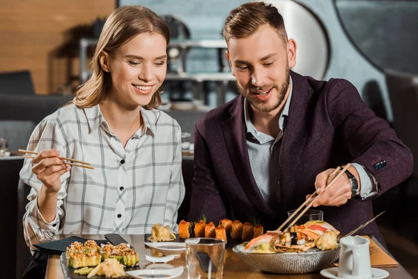 Attractive lovely couple eating together sushi rolls in restaurant — Stock Photo