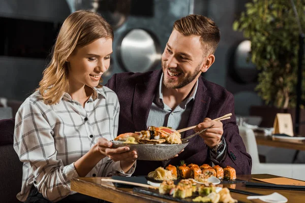 Feliz pareja joven y atractiva cenando en el restaurante - foto de stock