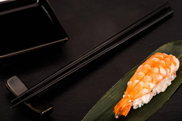 Primer plano de nigiri sushi con camarones servidos con palillos y salsa de soja sobre pizarra negra — Stock Photo