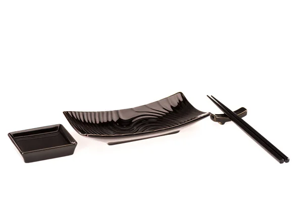 Platos negros para rollos de sushi y salsa de soja con palillos aislados en blanco - foto de stock