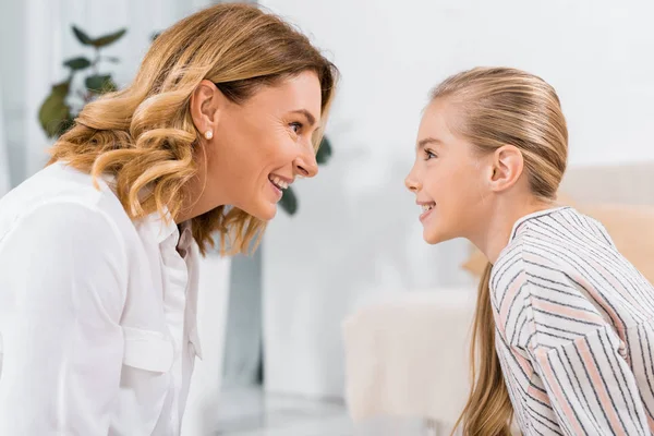 Side view of cheerful grandmother and her granddaughter looking at each other at home — Stock Photo