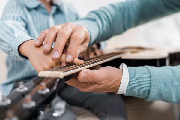 Imagen recortada del hombre enseñando a jugar con la guitarra acústica en casa - foto de stock