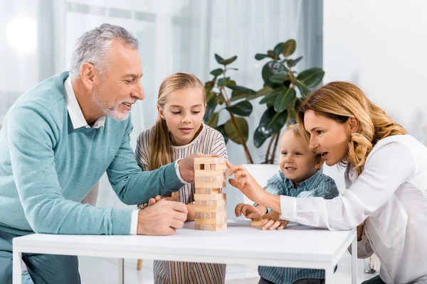 Felici nonni e nipoti giocare blocchi gioco torre di legno insieme a casa — Foto stock