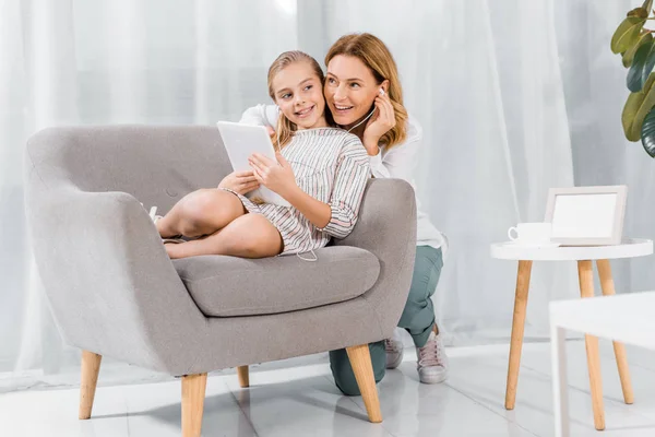 Lächelnde reife Frau und ihre entzückende Enkelin mit Kopfhörer und digitalem Tablet zu Hause — Stockfoto