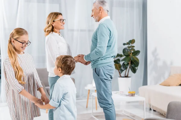 Brother and sister holdings hands of each other while their grandparents standing behind at home — Stock Photo