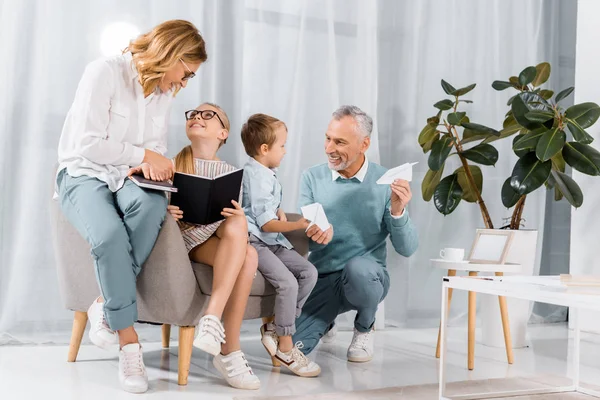 Fröhliche Großeltern und Enkel, die sich zu Hause auf dem Sofa vergnügen — Stockfoto