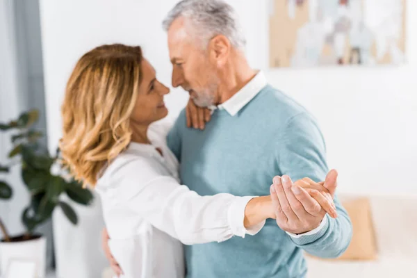 Selective focus of mature couple dancing face to face at home — Stock Photo