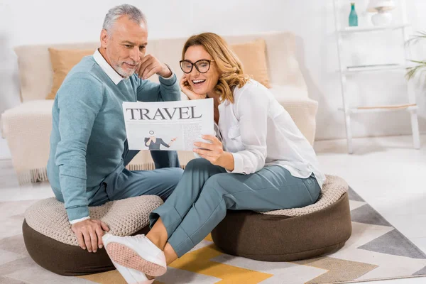 Smiling mature couple reading travel newspaper at home — Stock Photo
