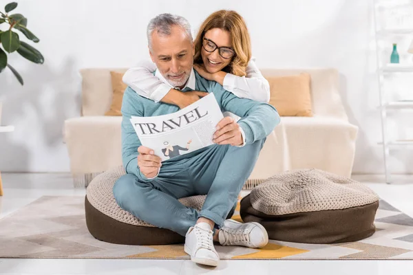 Glückliches Paar mittleren Alters liest zu Hause Reisezeitung — Stockfoto