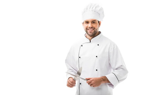 Guapo joven chef sosteniendo cuchillos de corte y mirando a la cámara aislada en blanco - foto de stock